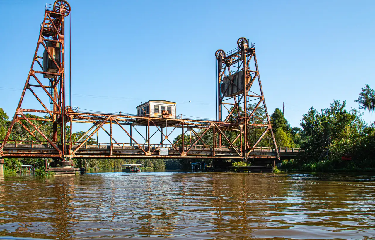 A covered swamp tour boat traveling through Louisiana marsh scenery
